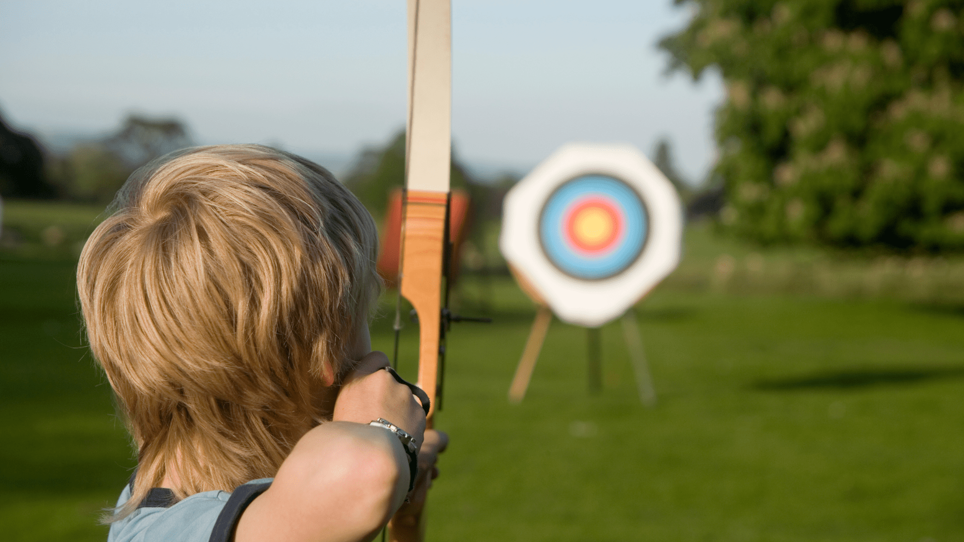 Youth aiming an arrow at a target.