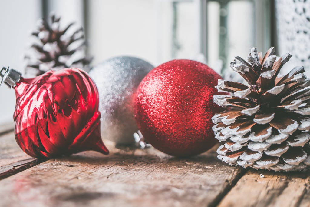 Close-up of Christmas ornaments and pine cones on a wooden table, creating a festive holiday atmosphere.